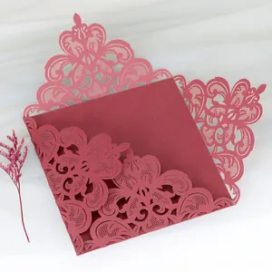 Detail of burgundy laser-cut lace wedding invitation card with intricate hollow pattern