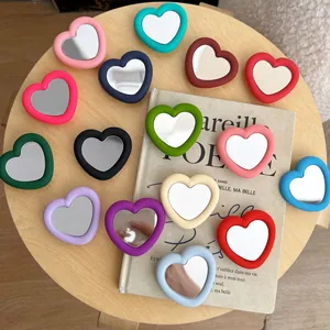 Variety of colorful heart-shaped silicone mirror phone grips displayed on a wooden surface