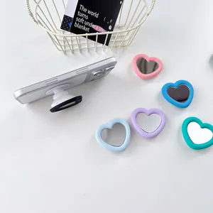 Close-up of colorful heart-shaped silicone mirror phone grips on white surface.