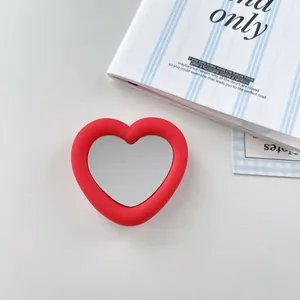 Close-up of a red heart-shaped silicone phone grip with a built-in mirror.