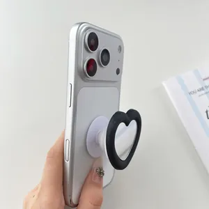 Close-up of heart-shaped mirror phone grip attached to a silver smartphone