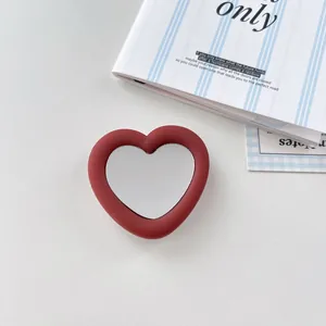 Close-up view of red heart-shaped silicone phone grip with built-in makeup mirror