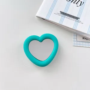 Close-up detail of a teal silicone heart-shaped phone grip featuring a built-in mirror