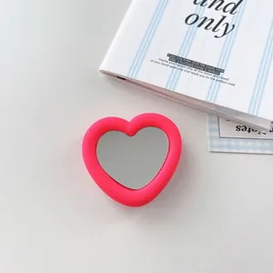 Close-up of heart-shaped mirror phone grip stand with vibrant pink silicone frame