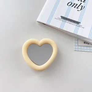 Detail view of a cream heart-shaped silicone phone grip with a small integrated mirror