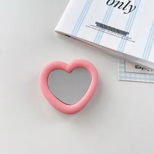 Detailed view of a stylish pink heart-shaped mirror phone grip with soft silicone finish.