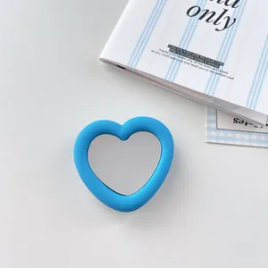 Detailed view of a blue heart-shaped silicone mirror phone grip on a white surface.