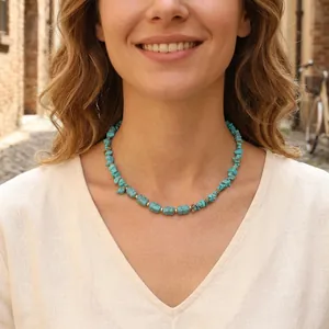 Irregular turquoise stone necklace on female model wearing a cream linen shirt outdoors