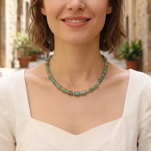Woman wearing an irregular green gemstone bead necklace with small gold spacer beads.