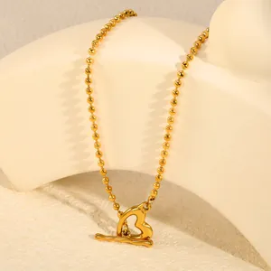 Gros plan du collier en acier inoxydable doré avec un pendentif cœur et fermoir OT
