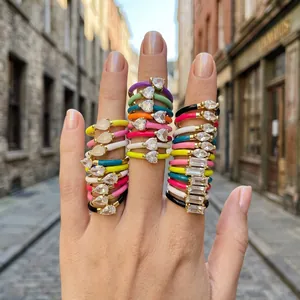 Close-up of colorful enamel stackable rings with teardrop cubic zirconia stones on fingers.