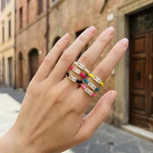 Stacked colorful enamel rings with baguette crystals on a hand in a street setting