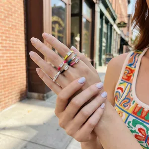 Detailed view of colorful enamel rings with baguette crystal accents on model's hand