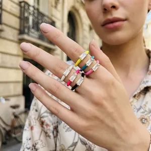 Stylish colorful enamel rings with baguette zirconia on a female hand in urban setting