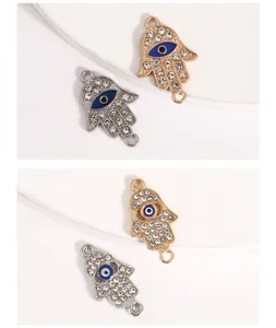 Detailed view of gold and silver Hamsa hand charms with evil eye enamel and rhinestones.