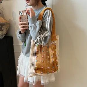 Fashionable hand-knit mesh tote bag with colorful pearl accents worn by a model