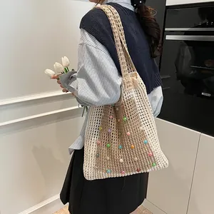 Beige knitted hollow-out shoulder bag featuring colorful pearl accents on a model