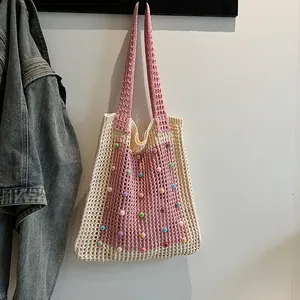 Detail of crochet tote bag featuring pink and beige knit with colorful pearl beads.