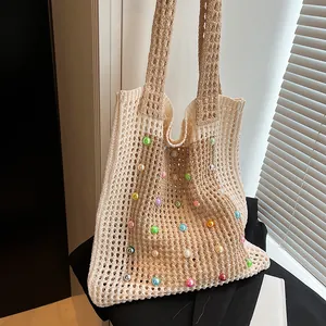 Close-up view of a beige crochet tote bag with colorful pearls and open knit design.
