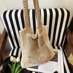 Detail of hand-knitted beige tote bag featuring vibrant colorful pearl beads embellishment