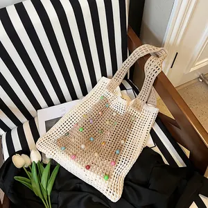 Detail of cream crochet knit shoulder bag featuring colorful bead accents and hollow design