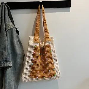 Close-up of a handmade crochet mesh tote bag with colorful beads hanging on a wall