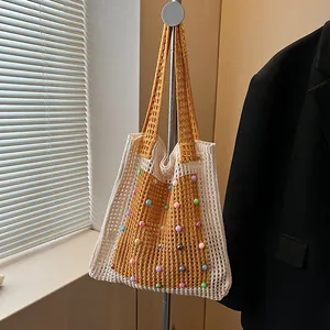 Detail view of a handmade crochet tote bag with colorful beads and hollow-out knit texture.