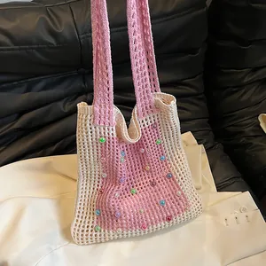 Close-up of a pink and white crochet knit tote bag featuring colorful bead accents
