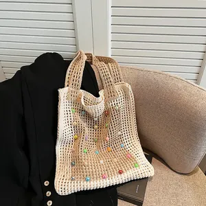 Close-up view of beige knitted tote bag featuring colorful bead embellishments and hollow-out design