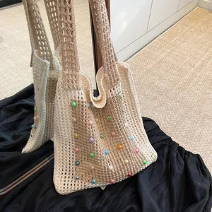 Close-up detail of a beige crochet hollow shoulder bag featuring colorful pearl bead accents