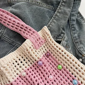 Close-up of a pink and beige knitted hollow-out tote bag with colorful pearl accents