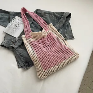 Detailed shot of a stylish pink and cream color-block knitted mesh tote bag on denim jacket