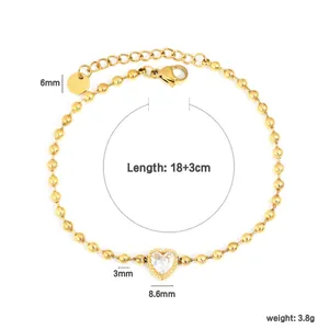 Détail d'un bracelet en perles dorées avec un centre en zircone en forme de cœur.