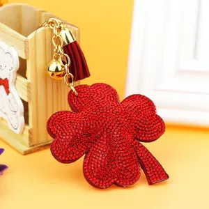 Close-up detail of a vibrant red rhinestone four-leaf clover keychain with tassel and bell
