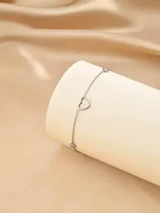 Vue détaillée d'un collier en acier inoxydable avec un cœur évidé et des zircons brillants.