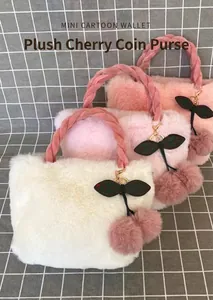 Close-up of cute plush cherry handbags in white and pink with fuzzy charms