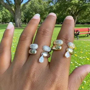 Detail of gold and silver pavé zircon open rings with water-drop charms on hand