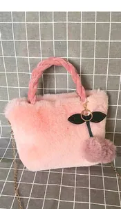 Detail of pink faux rabbit fur handbag with cute cherry plush charm and chain strap