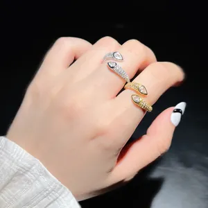 Detail view of gold and silver water-drop open rings with pavé white zircons on hand.