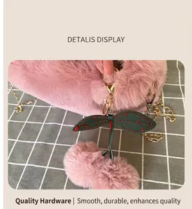 Close-up of pink faux fur texture and cherry pendant with gold chain hardware