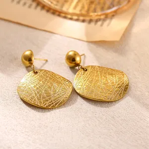 Macro detail of gold-plated geometric stainless steel earrings with textured finish