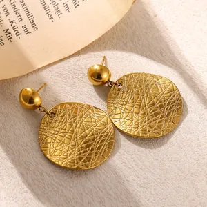 Detailed macro view of textured gold stainless steel disc earrings with etched pattern.