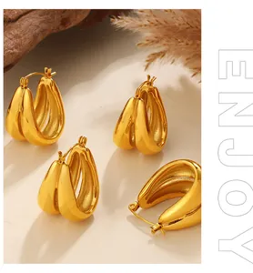 Macro detail of gold-plated twisted C-shape hoop earrings with a minimalist geometric design