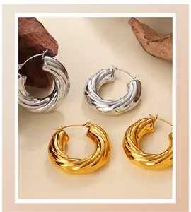 Close-up of elegant twisted C-shaped hoop earrings in gold and silver finish