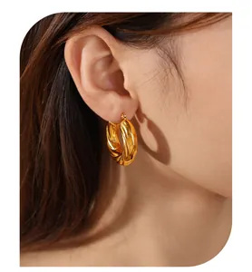 Macro detail view of elegant gold twisted C-shaped hoop earrings with textured surface