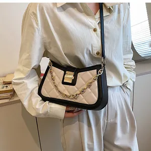 Close-up of stylish quilted two-tone crossbody underarm bag with gold chain strap