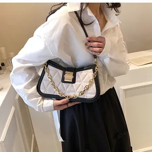 Elegant woman wearing a black and white quilted underarm bag with unique gold chain