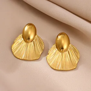 Macro view of chunky gold shell-shaped stainless steel earrings with textured fan design