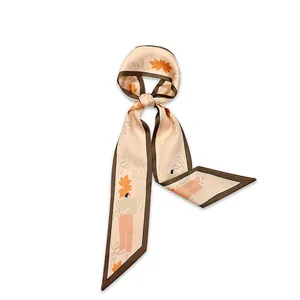 Close-up detail of narrow silk scarf with artistic orange leaf and figure patterns
