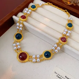 Detail of a vintage court style necklace with pearls and red/blue stones in a jewelry box